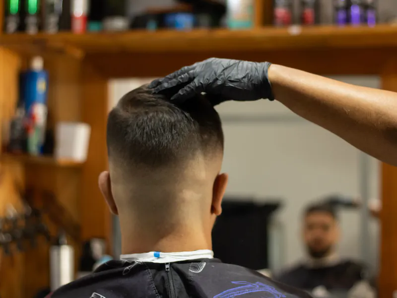 A barber styling a client's hair in a modern barbershop