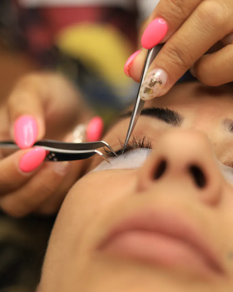 A technician applying individual lash extensions with tweezers