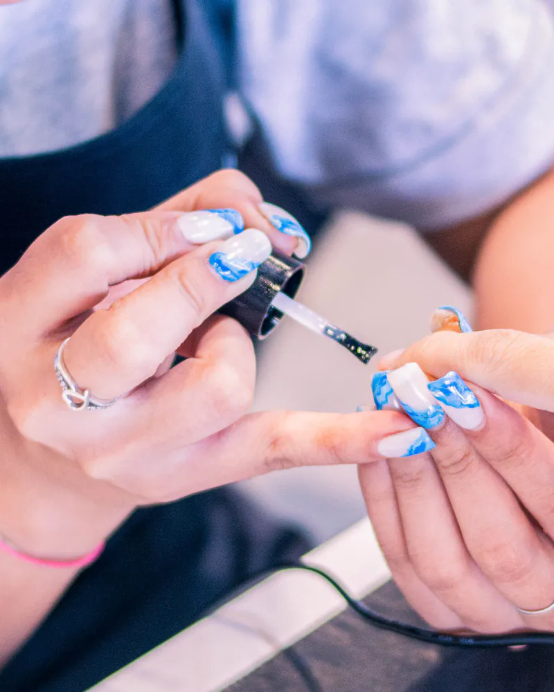A nail artist hand-painting a design onto a client's nail